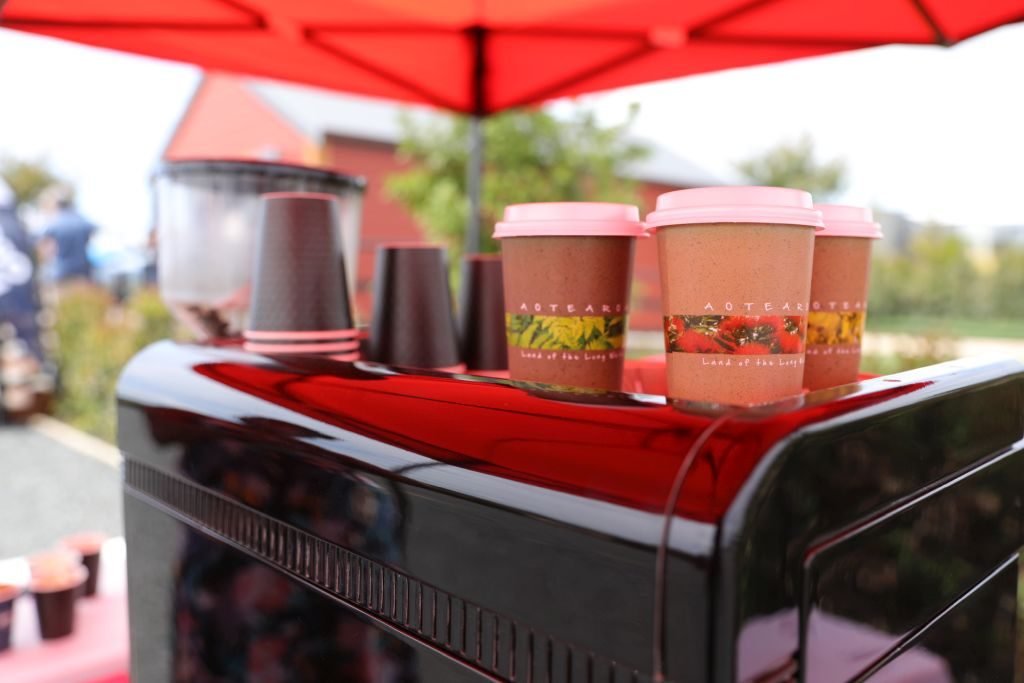 Printed takeaway cups stacked on a glossy red espresso machine