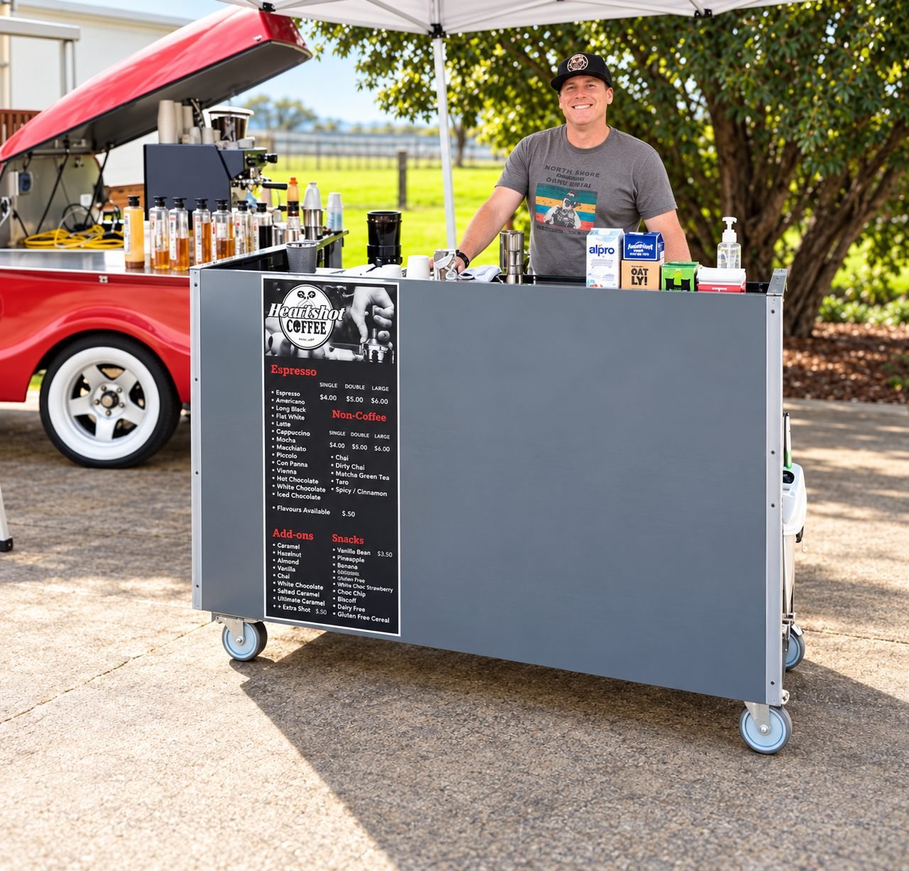 Barista behind the cart with the red trailer and gazebo behind