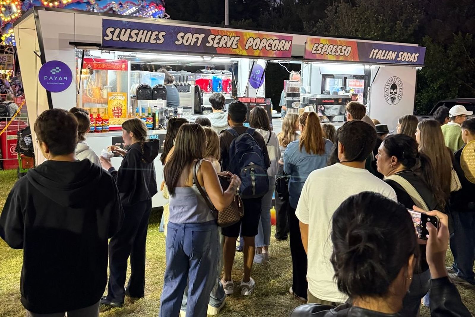 A big crowd standing in front of the Headshot trailer at night